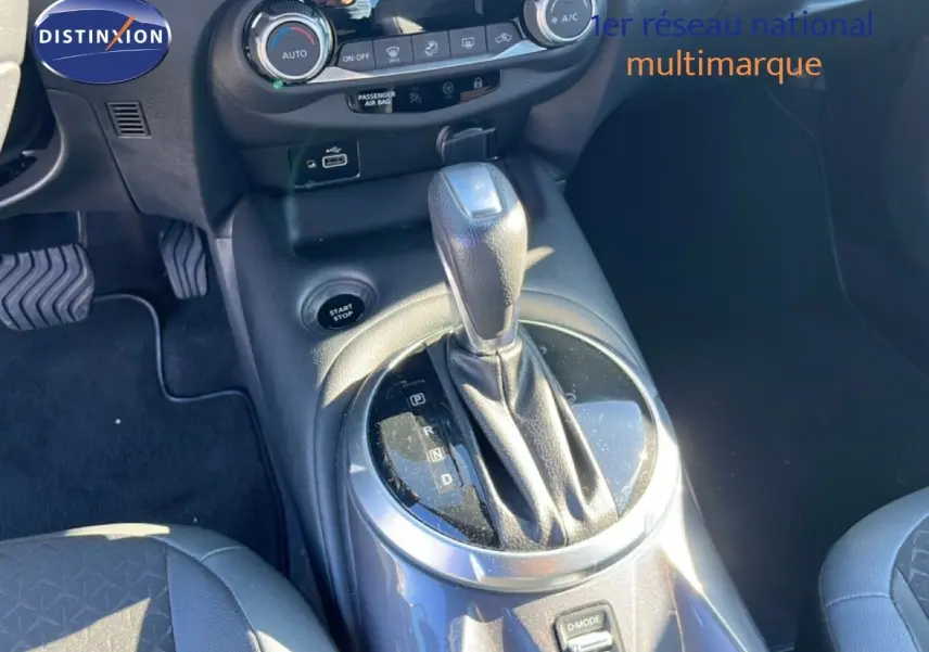 Gros plan sur la console centrale et levier de vitesse de la Nissan Juke Hybrid 2024 en gris squale métal, intérieur noir.
