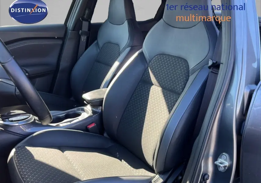 Vue intérieure côté conducteur du Nissan Juke Hybrid 2024, sièges en cuir noir et tissu gris, porte ouverte.