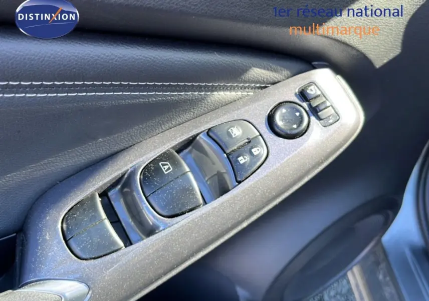 Gros plan sur les commandes de lève-vitres et rétroviseurs côté gauche d’un Nissan Juke gris squale métal 2024.