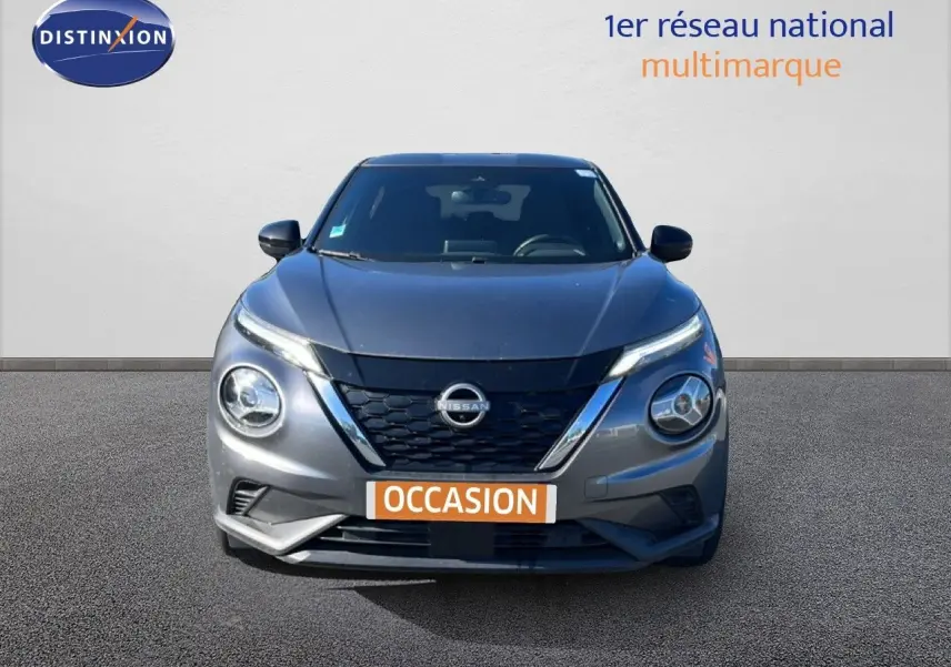 Vue avant d'un Nissan Juke Hybrid gris squale métal avec calandre noire et phares ronds distinctifs.