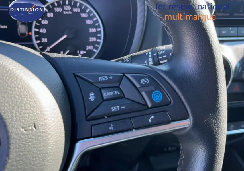 Gros plan sur les commandes au volant à droite du tableau de bord du Nissan Juke Hybrid gris squale métal 2024.
