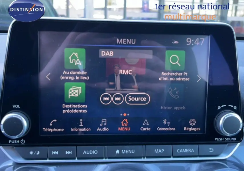 Écran tactile central du Nissan Juke Hybrid 2024, affichant le menu audio avec commandes autour, intérieur gris.