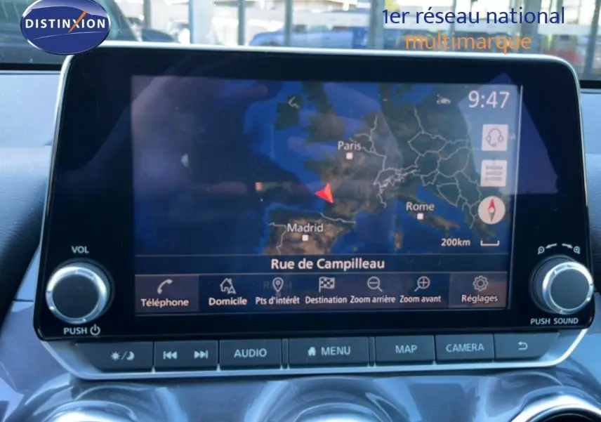 Vue intérieure du tableau de bord du Nissan Juke Hybrid 2024, écran tactile GPS affichant une carte de navigation.