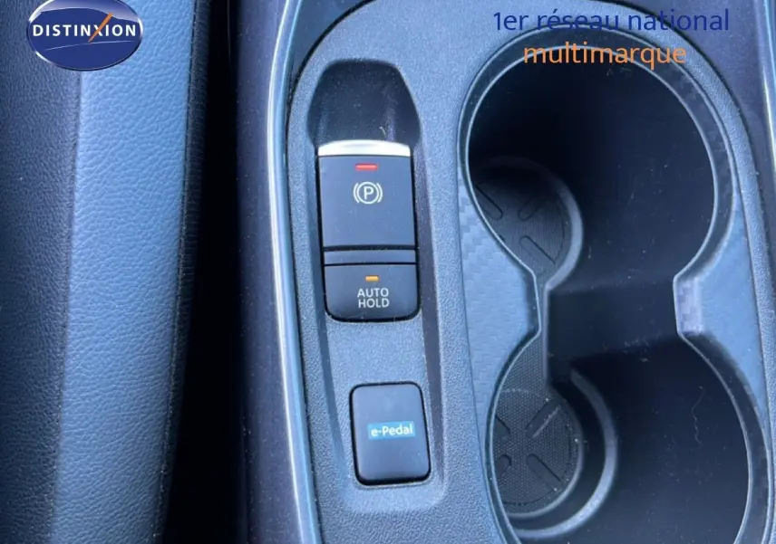Vue rapprochée de la console centrale noire du Nissan Juke Hybrid 2024 avec boutons de frein à main, auto hold et e-Pedal.
