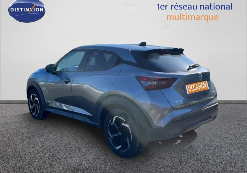 Vue 3/4 arrière droite d'un Nissan Juke hybride gris squale métal avec jantes noires et toit foncé.
