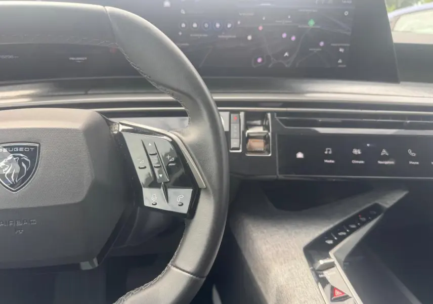 Vue intérieure centrée sur le volant cuir noir et le cockpit numérique du Peugeot 5008 Hybrid 2025.