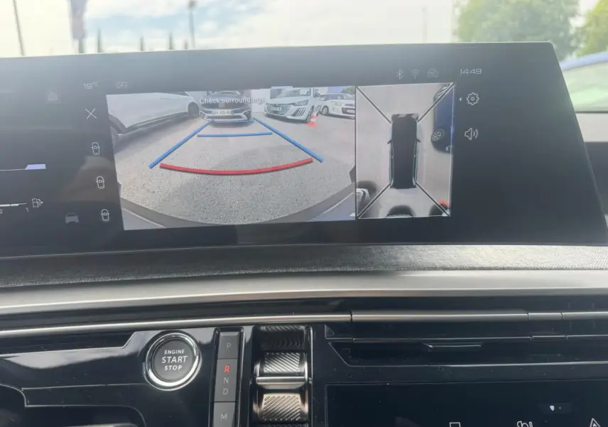 Vue intérieure du tableau de bord du Peugeot 5008 Hybrid 2025, écran affichant la caméra de recul et l'aide au stationnement.