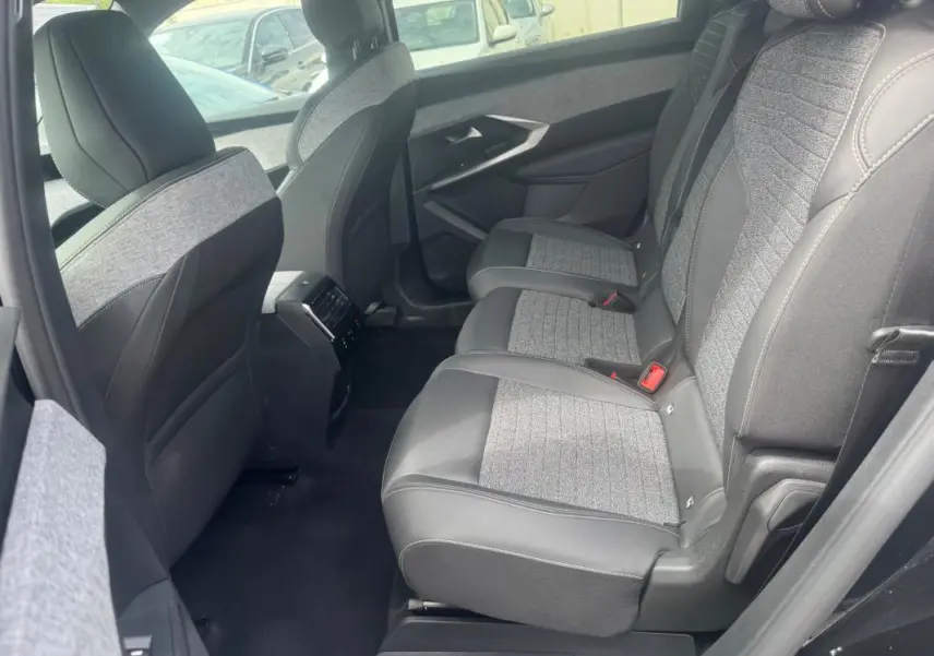 Vue latérale droite de l'intérieur arrière du Peugeot 5008 noir, sièges tissu et cuir avec console centrale et aérateurs.
