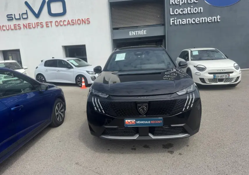 Peugeot 5008 Hybrid noir vue de face, avec calandre distinctive et feux à LED verticaux allumés.