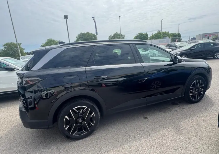 Peugeot 5008 Hybrid noir vue de profil côté gauche, avec jantes alliage 19 pouces et barres de toit visibles.