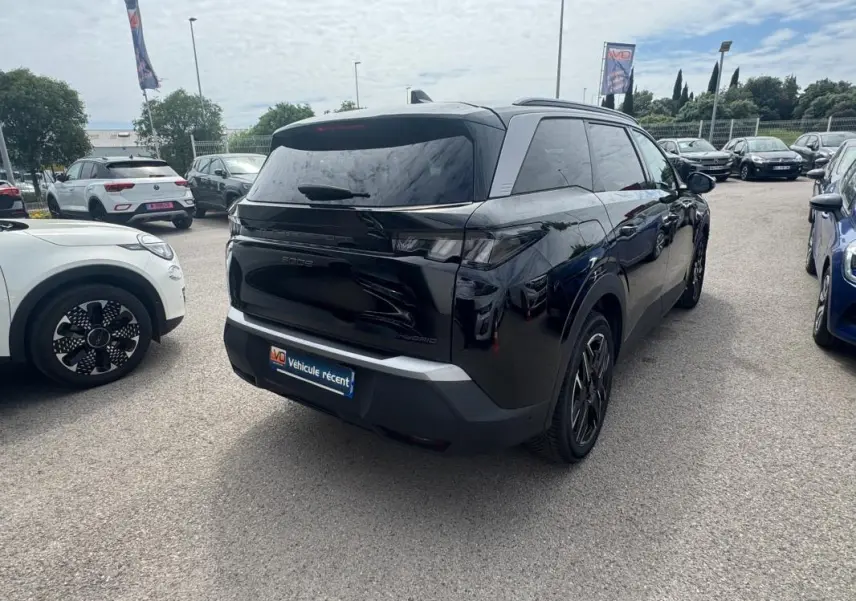 Peugeot 5008 Hybrid noir vu 3/4 arrière droit, avec barres de toit et jantes alliage 19 pouces visibles.