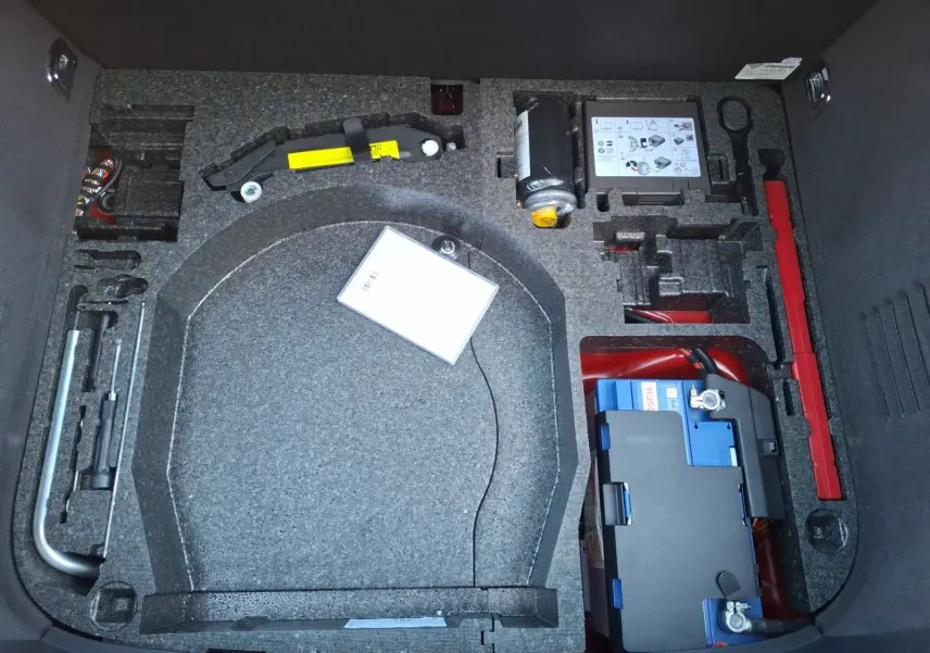 Coffre ouvert d’un Audi TT 3.2 V6 Quattro rouge de 2007, montrant le rangement pour roue de secours et outils intégrés.