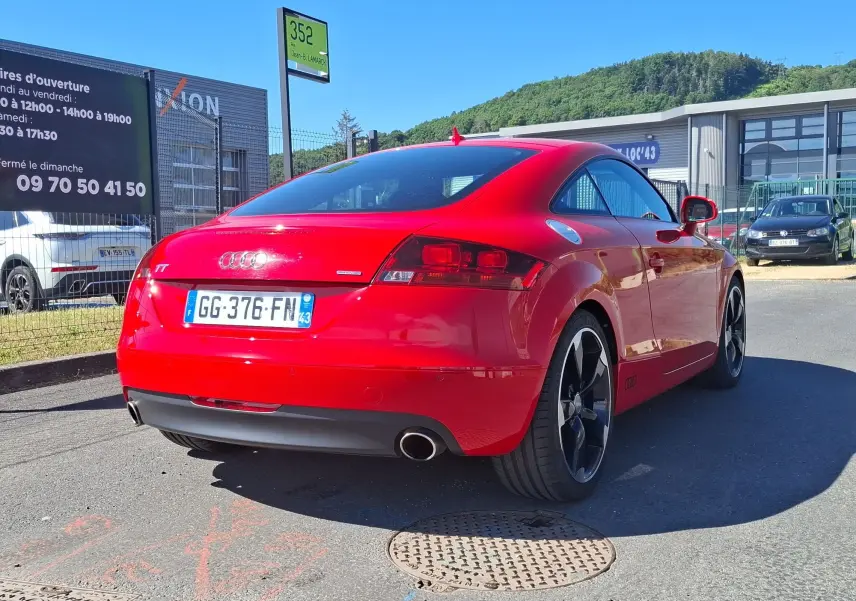 Audi TT 3.2 V6 Quattro rouge vue 3/4 arrière droit, avec jantes alliage noires et double sortie d'échappement.