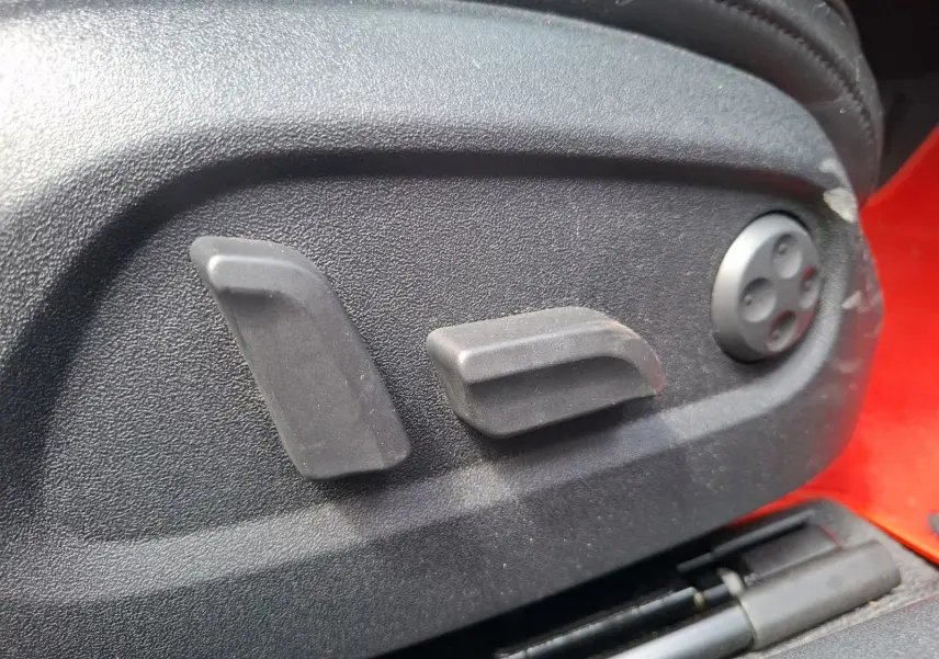 Détail des commandes de réglage électrique du siège côté conducteur d’un Audi TT rouge, vue rapprochée.