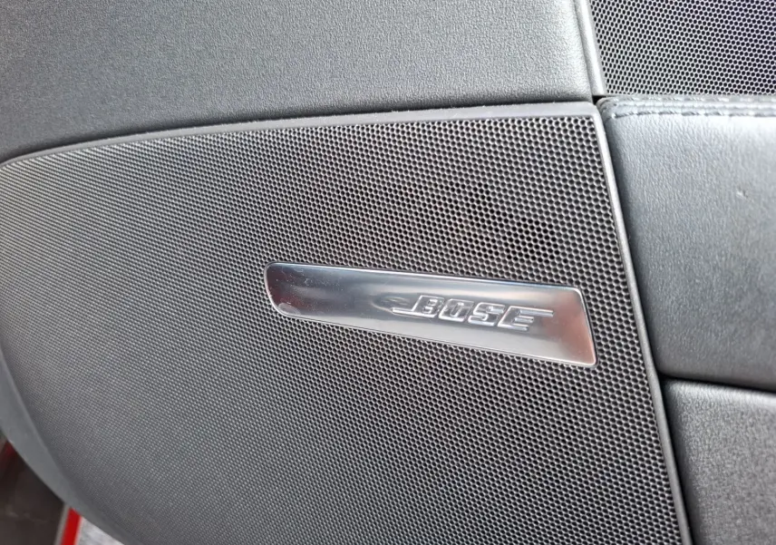 Gros plan sur le haut-parleur Bose intégré dans la porte intérieure d'une Audi TT rouge, version 3.2 V6 Quattro.