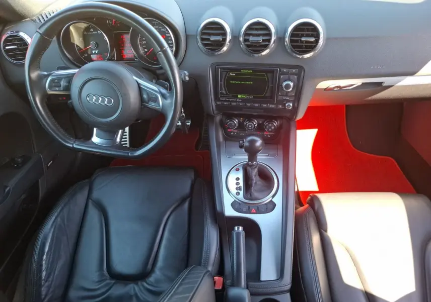 Vue intérieure de l'Audi TT 3.2 V6 Quattro 2007, sellerie cuir noire, volant avec palettes et console centrale argentée.