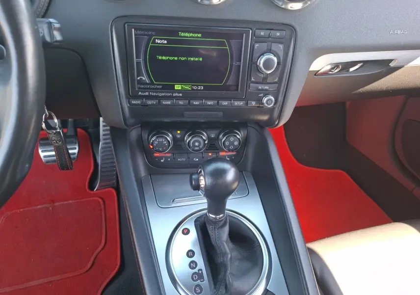 Vue rapprochée de la console centrale de l'Audi TT 3.2 V6 Quattro 2007 avec levier de boîte auto et tapis rouges.
