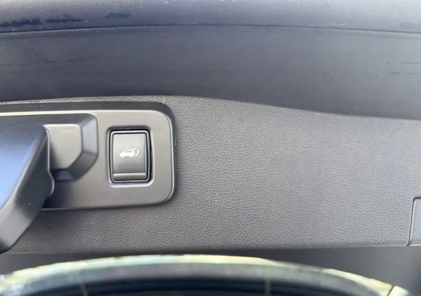 Bouton d'ouverture électrique du hayon dans l'intérieur noir texturé d'un Renault Austral Hybrid 2025.