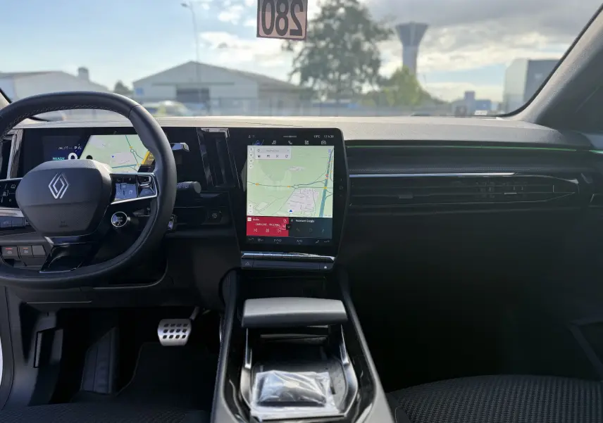 Vue intérieure frontale du tableau de bord du Renault Austral Hybrid avec écran tactile central et volant multifonction noir.