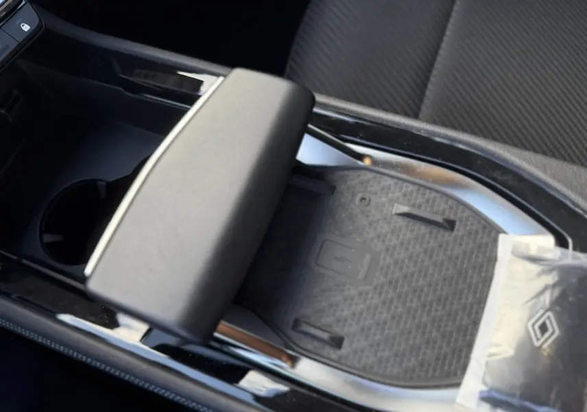 Gros plan sur la console centrale noire du Renault Austral Hybrid 2025, avec accoudoir et espace de rangement.
