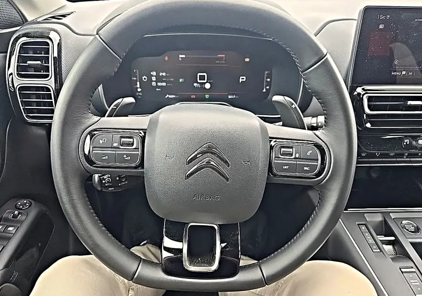 Vue rapprochée du volant cuir noir multifonction d’un Citroën C5 Aircross 2025 avec tableau de bord numérique et écran tactile.