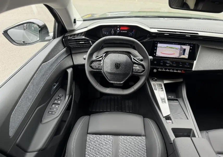 Vue intérieure de face du poste de conduite de la Peugeot 308 2026 gris sélénite avec écran tactile et volant compact.