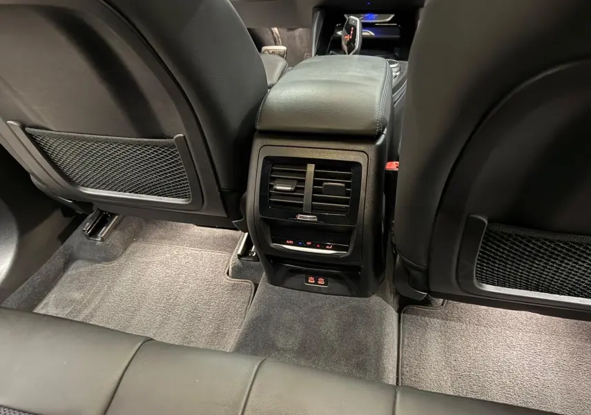 Vue arrière de l'habitacle noir d'une BMW X4 XDrive 20d 2020, montrant la console centrale avec aérateurs et commandes climatiques.