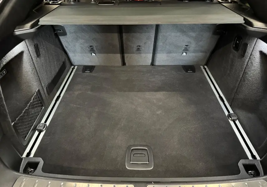 Coffre spacieux de BMW X4 XDrive 20d 2020 en Carbonschwarz, vue intérieure arrière avec revêtement noir et rails de fixation.
