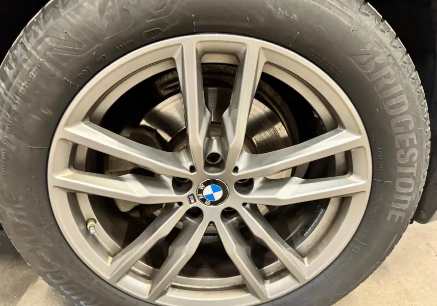 Gros plan sur la jante alliage argentée avec logo BMW au centre, montée sur pneu Bridgestone.