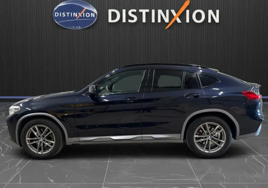 BMW X4 XDrive 20d M SPORT 2020 en carbonschwarz, vue profil côté gauche sur fond intérieur noir avec logo Distinxion.
