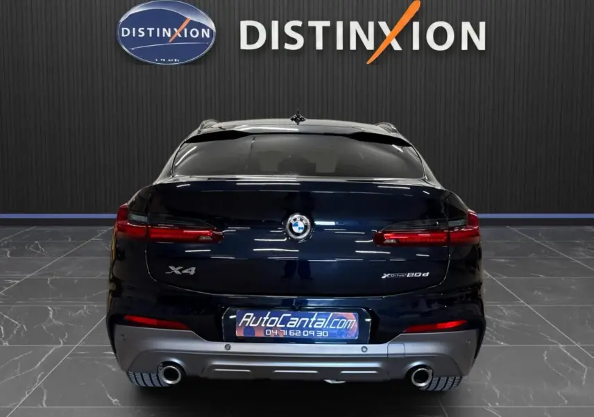 Vue arrière d'un BMW X4 XDrive 20d 2020 en Carbonschwarz, avec feux LED et double sortie d'échappement visibles.
