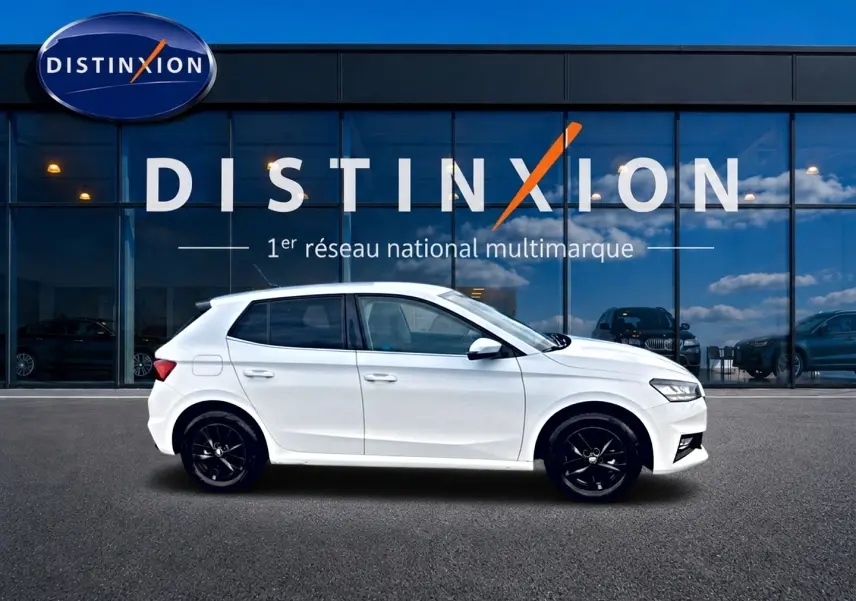 Vue de profil côté gauche d'une Skoda Fabia blanche 2025 avec jantes noires, devant une vitrine Distinxion.
