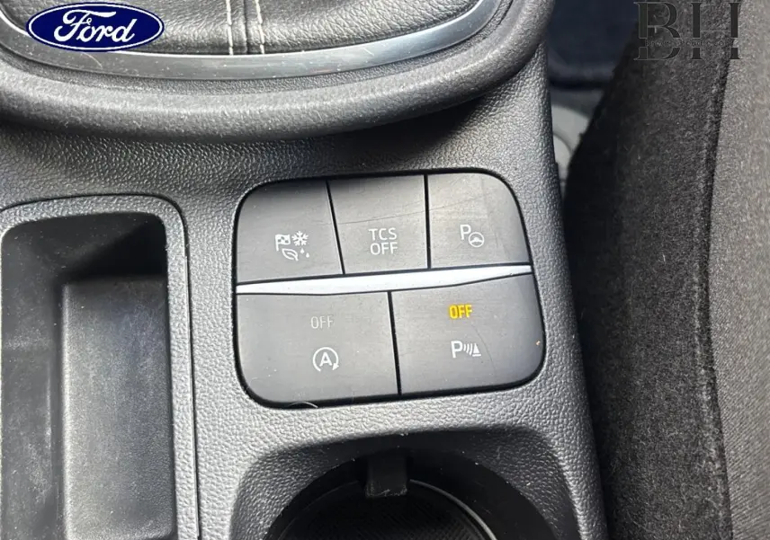 Gros plan sur les commandes de la console centrale du Ford Puma gris, avec boutons d’aide à la conduite et rangement.