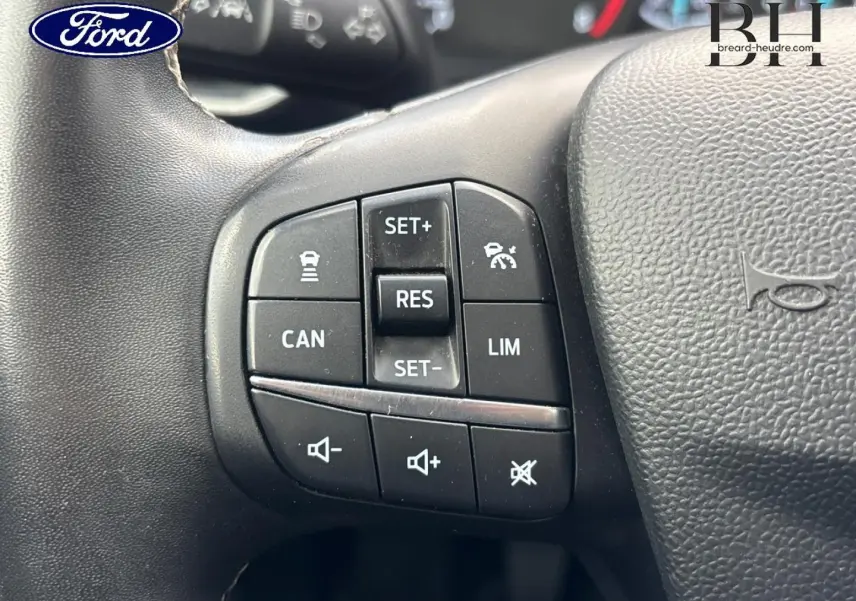 Gros plan sur les commandes multifonctions au volant noir du Ford Puma gris Solar Métallisée, version 2023 Titanium Business.