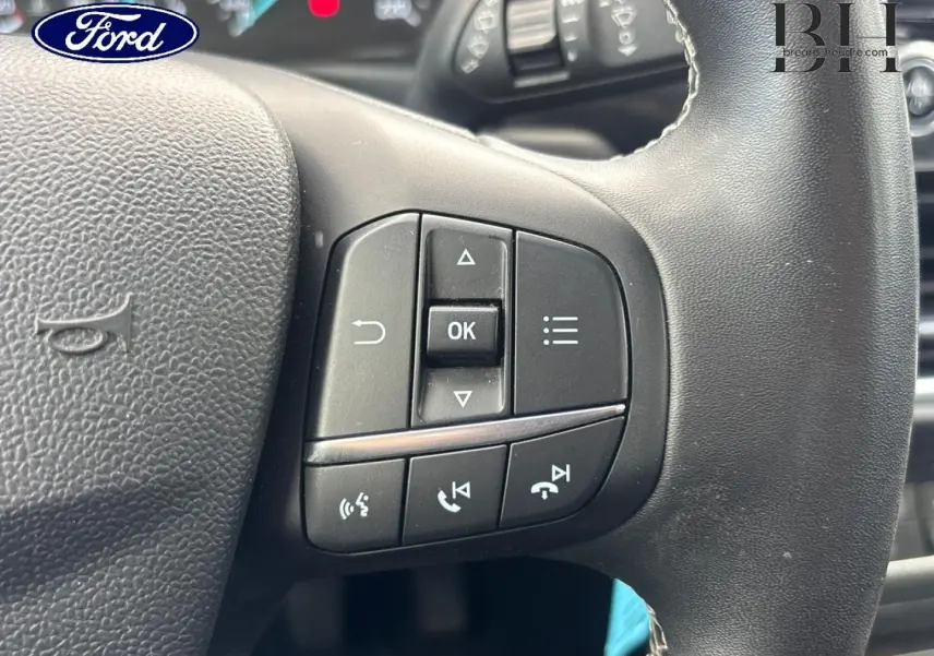Gros plan sur les commandes multifonctions noires à droite du volant de la Ford Puma 2023, intérieur gris.