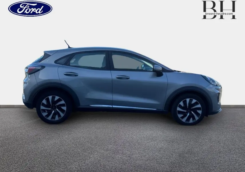 Ford Puma gris Solar métallisé vu de profil côté gauche, avec jantes alliage bicolores et poignées de porte ton caisse.