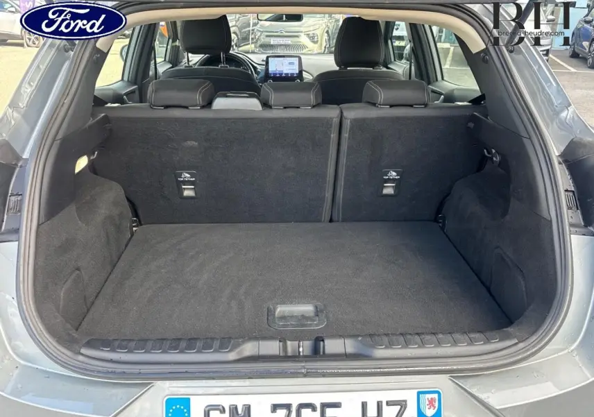 Coffre ouvert d’un Ford Puma gris Solar métallisé, vue arrière montrant l’espace de chargement et la banquette rabattue.