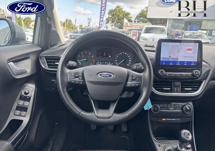 Vue intérieure centrée sur le volant multifonction et l’écran tactile du Ford Puma 2023, avec tableau de bord noir.