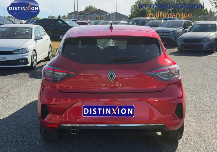 Vue arrière d'une Renault Clio orange Valencia 2025 avec feux LED et sortie d'échappement chromée visible.