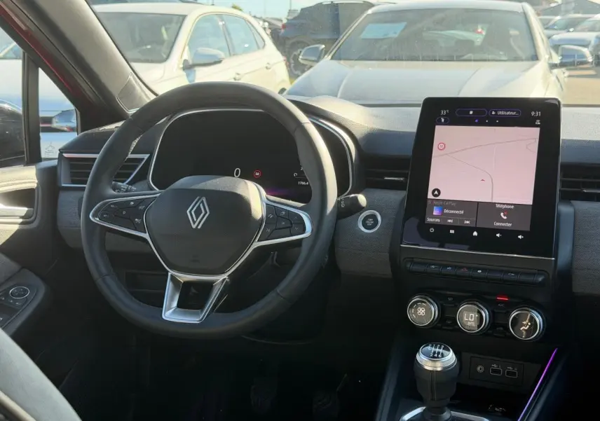 Intérieur de la Renault Clio 2025 vu de face, volant multifonction, écran tactile central et levier de vitesses manuel.
