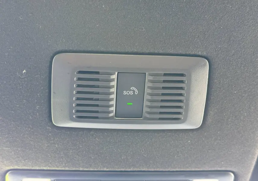 Bouton SOS noir avec icône téléphone et témoin vert, intégré dans le plafond intérieur d'une MG3 blanche.