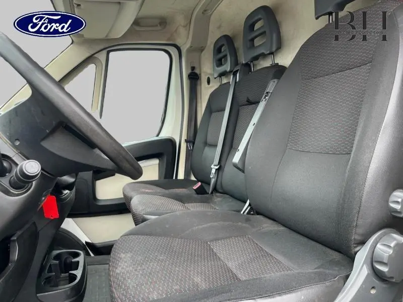 Intérieur côté conducteur du Citroën Jumper blanc Banquise, montrant les sièges tissu gris foncé et le volant noir.