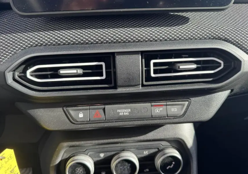 Détail intérieur du tableau de bord du Dacia Jogger gris, montrant les aérateurs centraux et les commandes climatisation.
