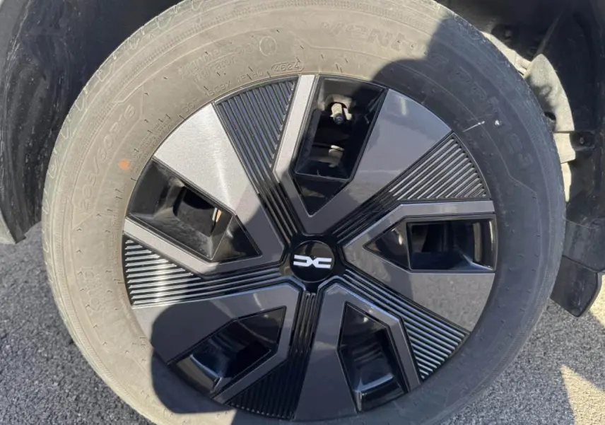 Gros plan sur la roue avec enjoliveur noir et gris du Dacia Jogger Gris Schiste 2025, détail du pneu visible.