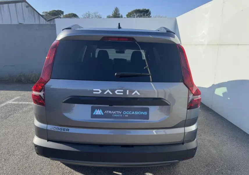 Vue arrière d'un Dacia Jogger gris schiste métal avec feux arrière verticaux et logo DACIA visible.