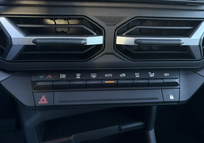 Détail de la console centrale noire du Dacia Duster 2025, avec commandes climatisation et aérateurs hexagonaux.