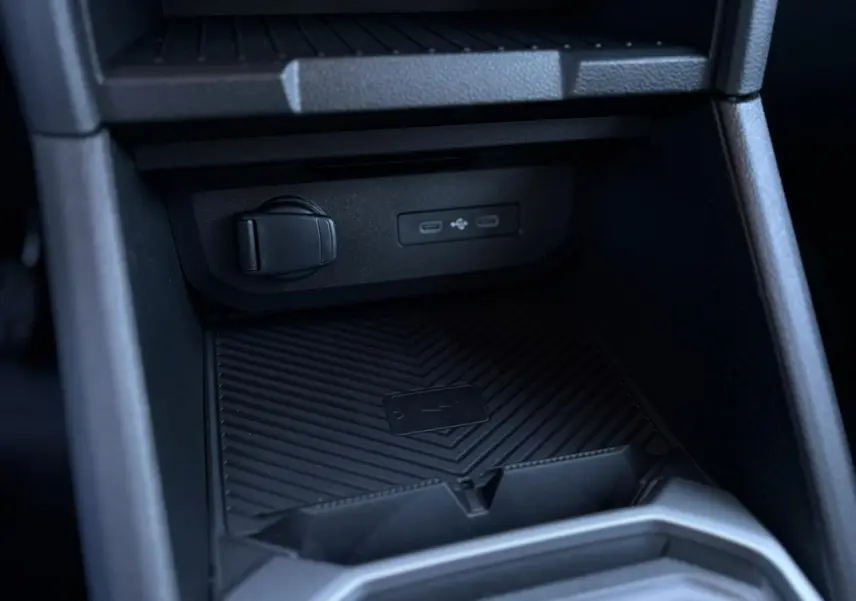 Gros plan sur la console centrale noire du Dacia Duster 2025, montrant les ports USB et un espace de rangement.