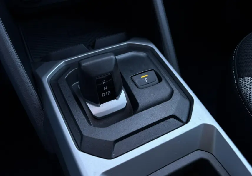 Gros plan sur le levier de vitesses automatique et bouton parking du Dacia Duster 2025 intérieur noir et gris.