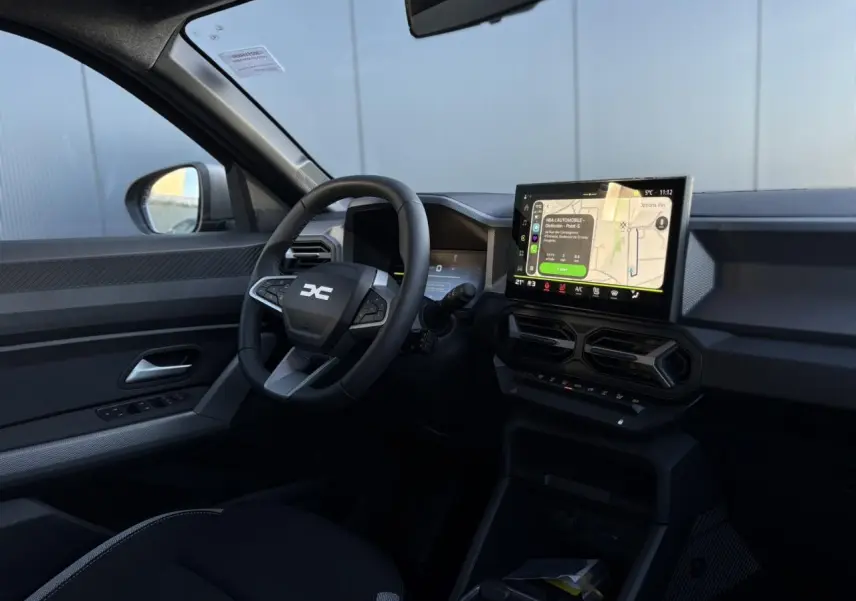 Vue intérieure côté conducteur du Dacia Duster 2025 noir nacré, avec tableau de bord digital et écran tactile central.