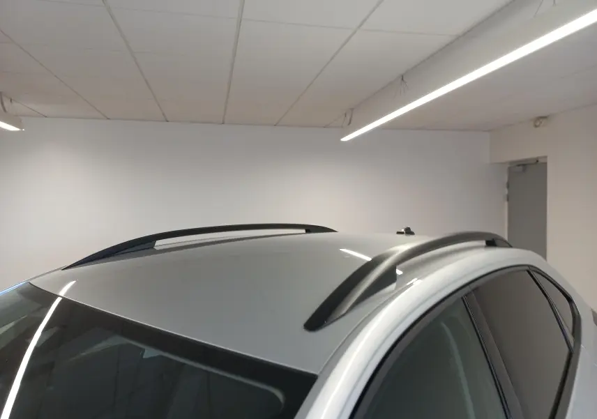 Vue rapprochée du toit argenté métallisé d’un Volkswagen Taigo 2025 avec barres de toit noires en intérieur.